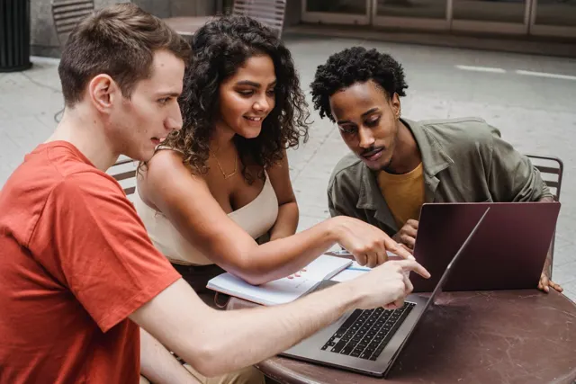 Friends helping each other with a laptop